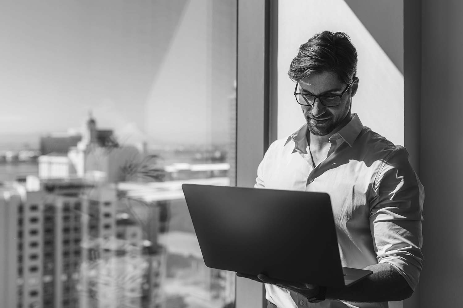 man in glasses working beside office window